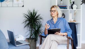 Professional Psychotherapy online. Middle aged female Psychologist having video call consultation on laptop while sitting on armchair