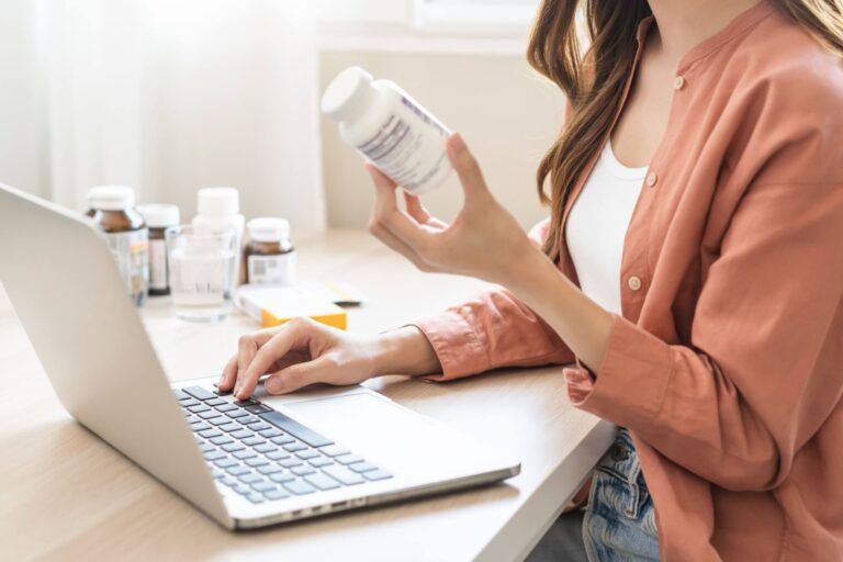 asian young woman, girl working from home using computer, typing or searching prescription on medicine label about vitamins information online
