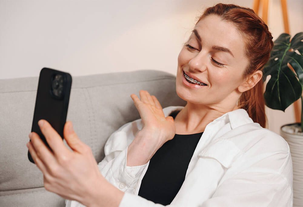 Portrait of mature woman showing braces on her teeth on video call
