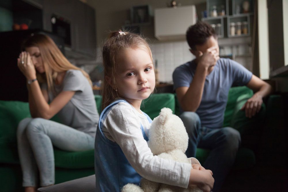Frustrated little girl upset tired of parents fight looking at camera