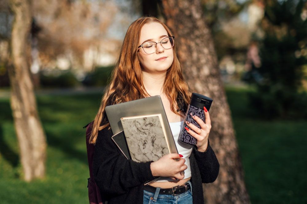Mental Health Challenges Facing College Students. Candid portrait of young student girl with laptop and books outdoor