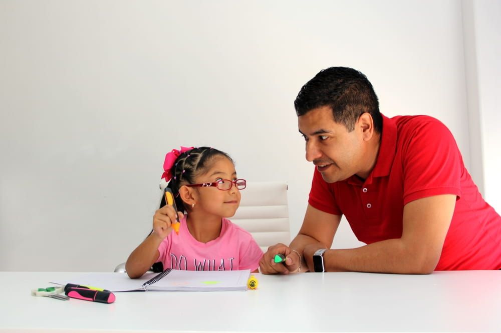 Latino dad and daughter draw in a notebook to improve skills with Autism Spectrum Disorder (ASD)