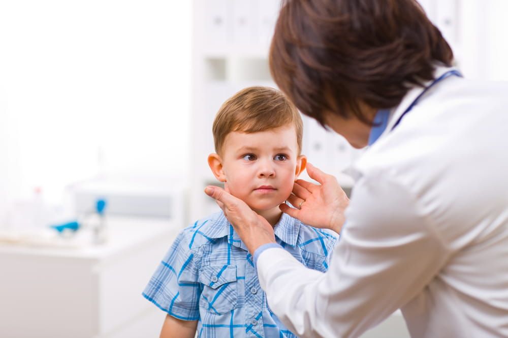 Senior female doctor examining little child boy.