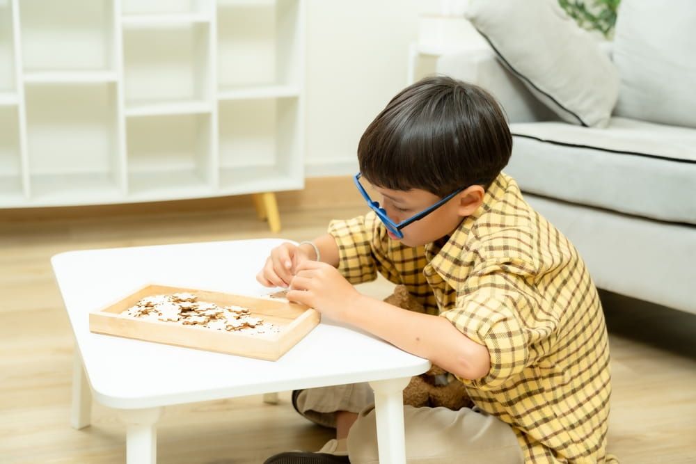 Asian boy with ADHD concentrating quietly on puzzle therapy activity alone in psychological clinic