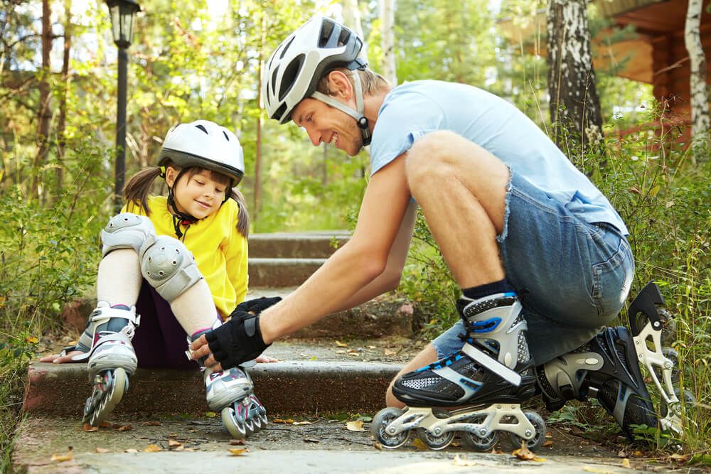 portrait of a sports dad and daughter in a helmet. Dad with his little daughter on the skates