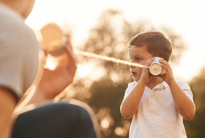 With string can phone. Father and little son are playing and having fun outdoors.