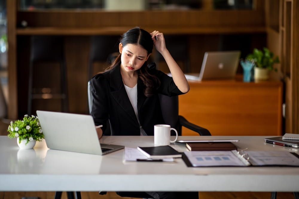 Shot of Asian young businesswoman looking stressed while sitting in her office in front of the laptop.