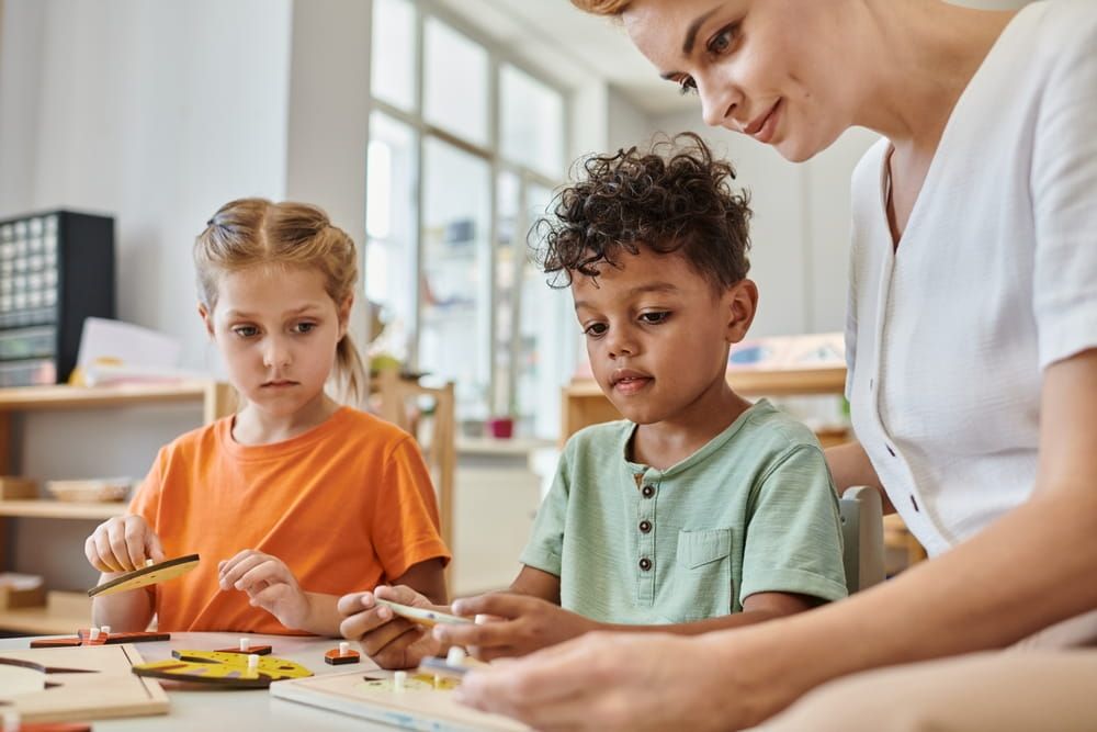 interracial children playing with didactic montessori material near female teacher, diversity