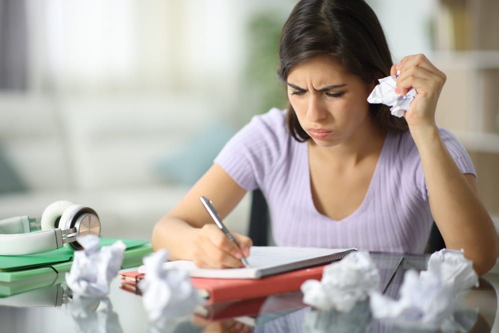 Frustrated student crumpling papers at home