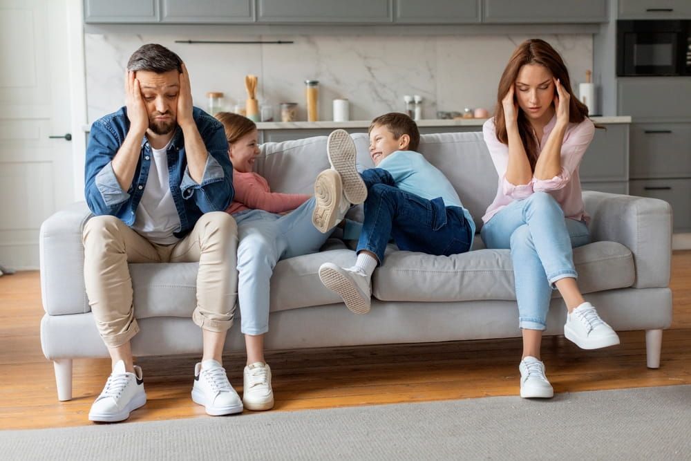 A European kids enjoys a playful home interaction with the leg fight, showcasing love and vibrant relationships, stressed parents sitting aside