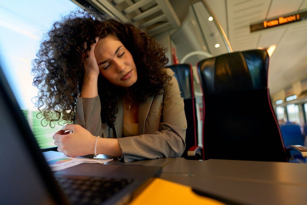 Young lady experiencing a headache from work fatigue on her train journey, needing a break.
