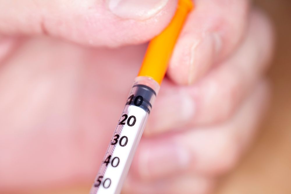 Close up of handheld unopened needle and syringe