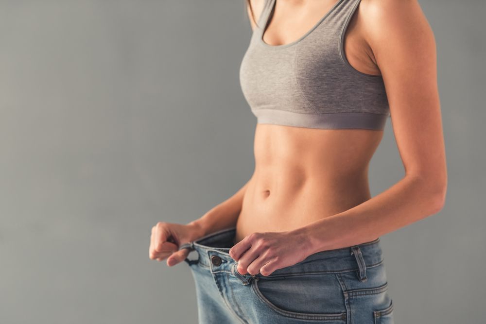 Cropped image of girl pulling her big jeans and showing weight loss