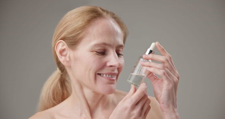 Caucasian middle aged woman in her 50s holding a bottle of skin care serum