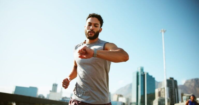 Man, fitness and running with watch in city for workout app, exercise or tracking performance