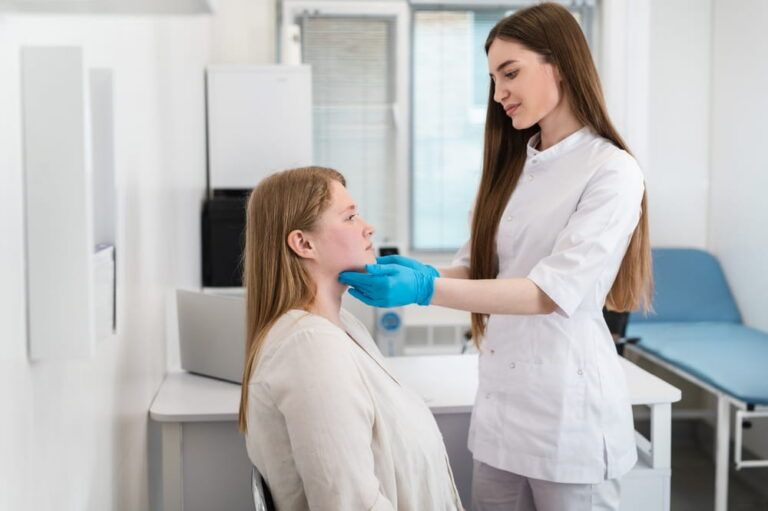 An endocrinologist wearing rubber gloves palpates the lymph nodes and thyroid gland of a patient with excess weight and acne.