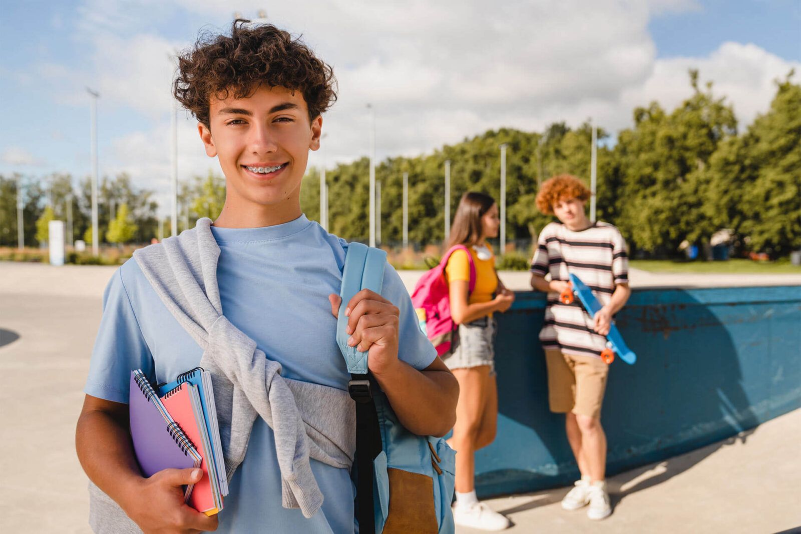 Handsome curly teen high school boy guy with braces bag in casual clothes