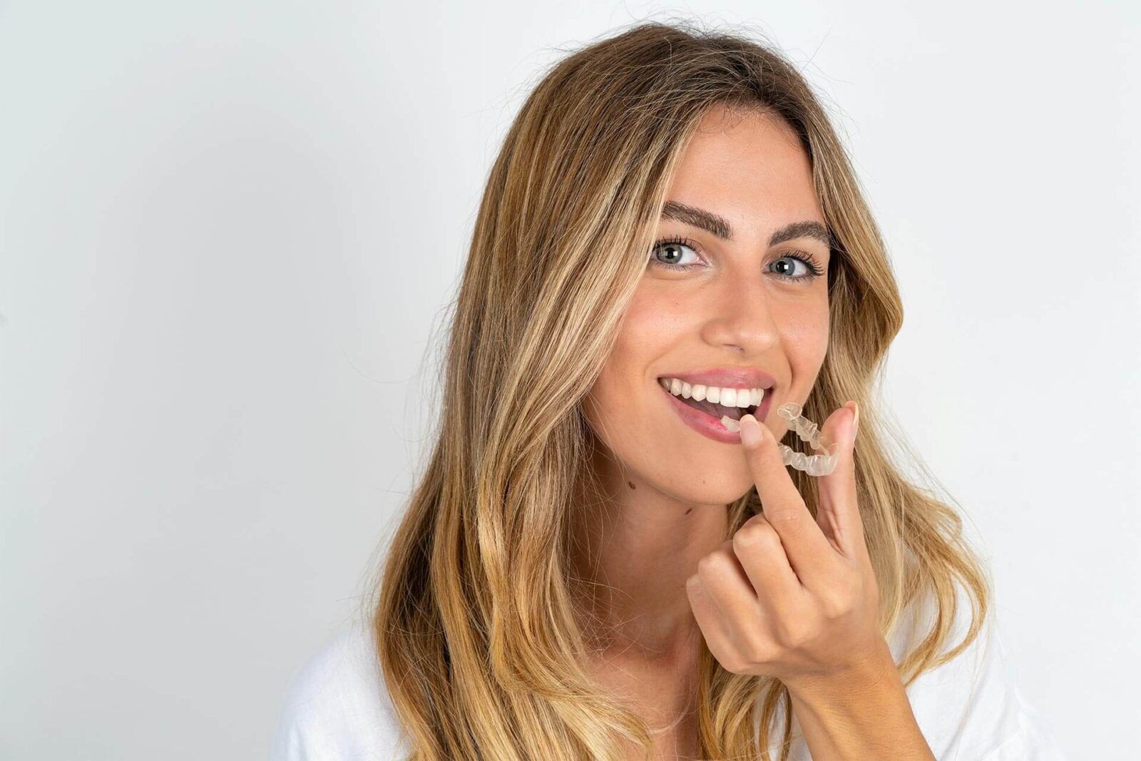 Young beautiful woman holding an invisible aligner