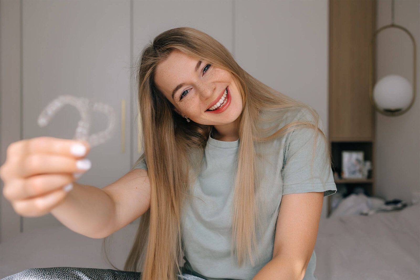 A cheerful woman proudly displays clear aligners