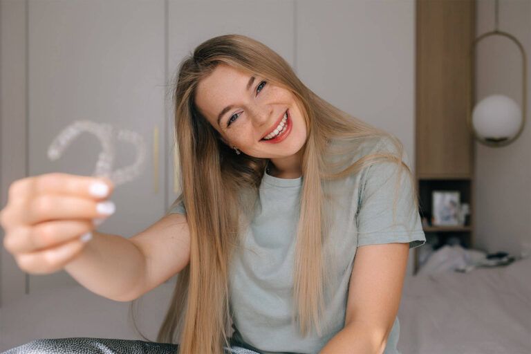 A cheerful woman proudly displays clear aligners