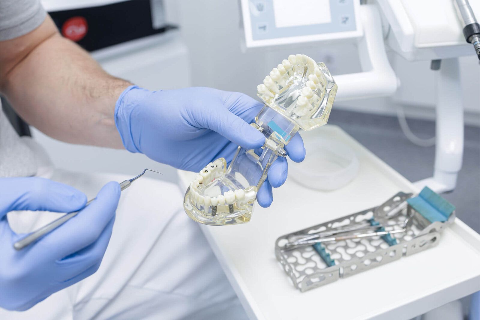 Dentist holds implant jaw model and explains tooth replacement options