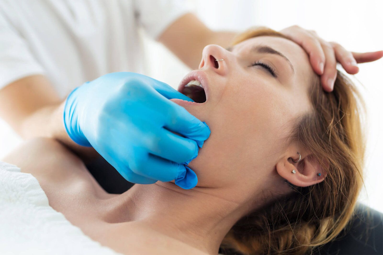 Young physiotherapist doing a face treatment to the patient in a physiotherapy room