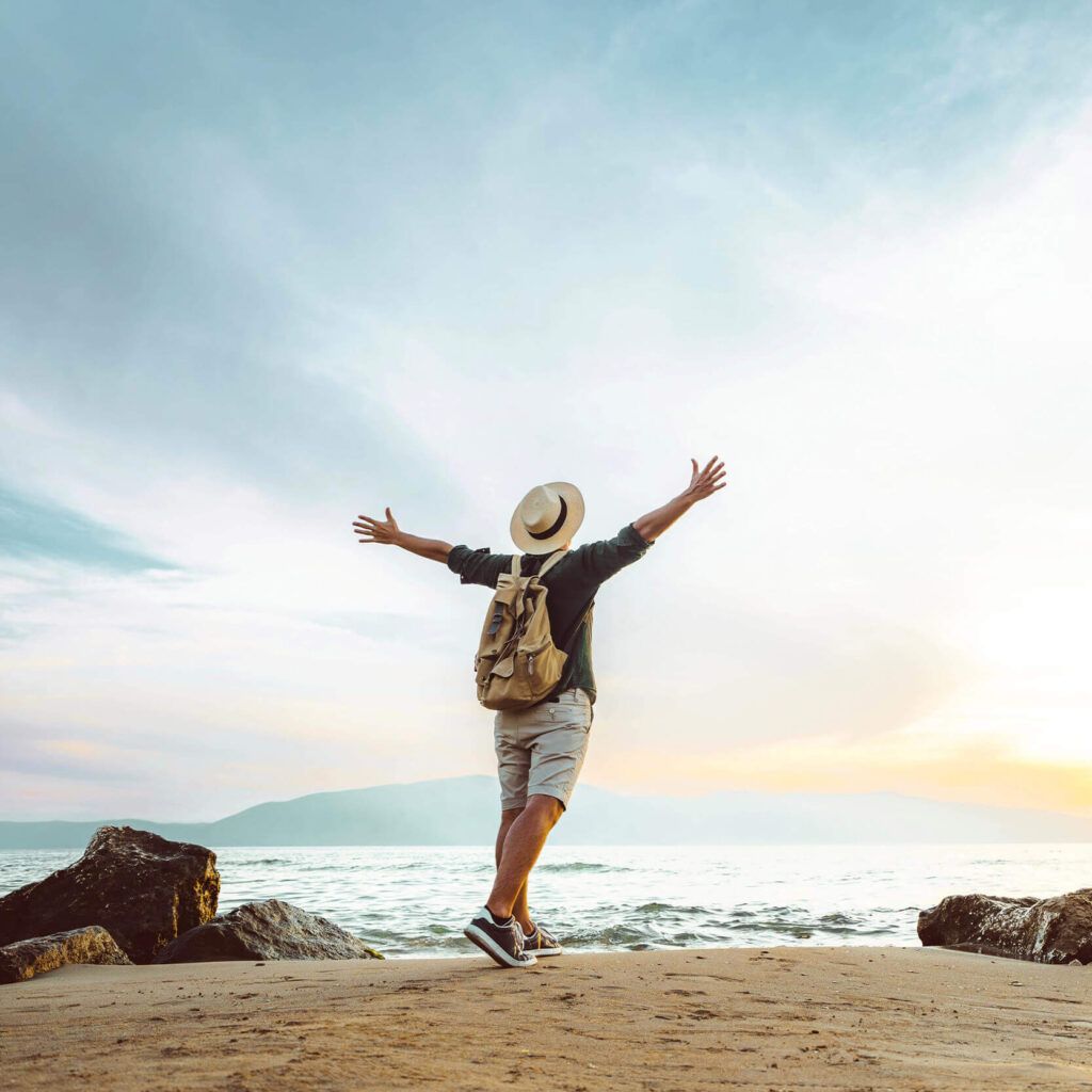 a person standing on a beach with their arms outstretched
