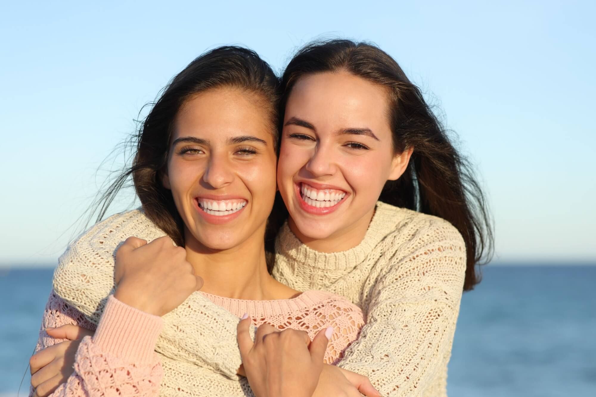 Front view portrait of two happy friends showing perfect smile on the beach
