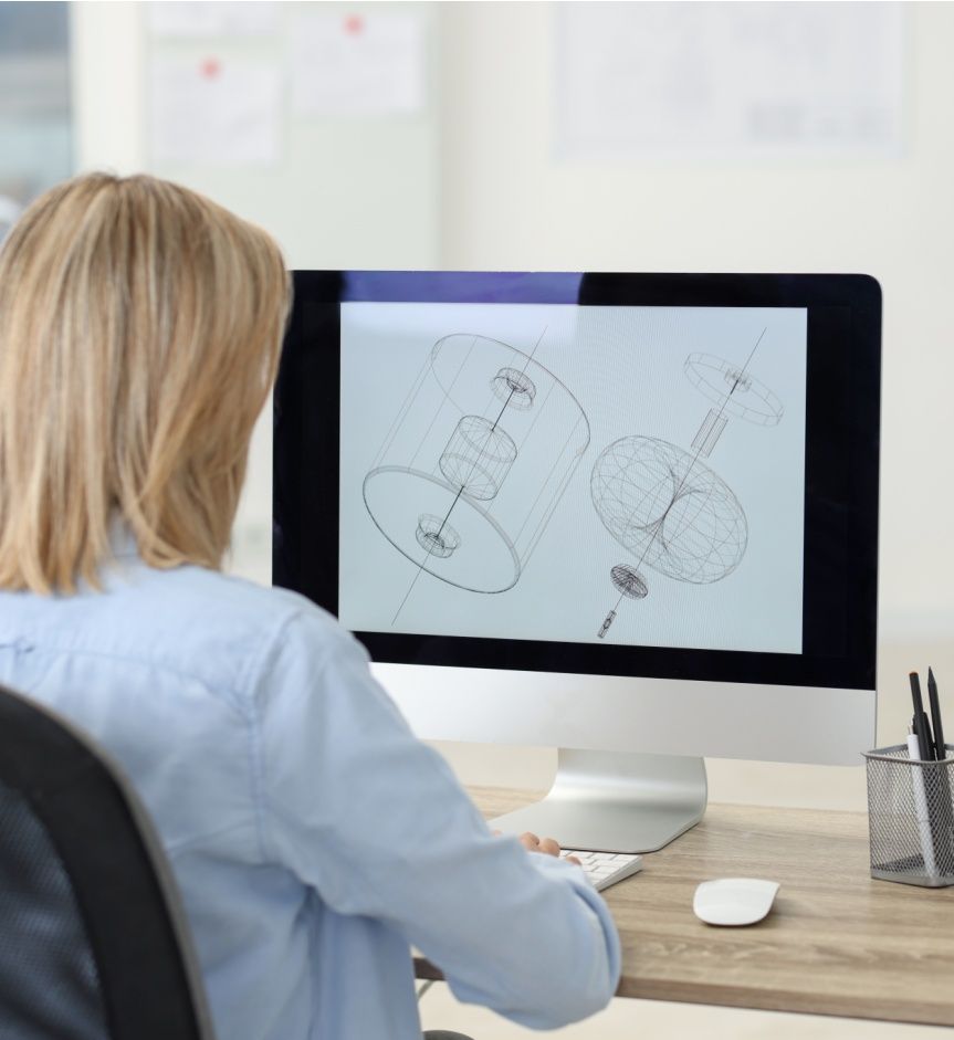 Technician making digital engineering drawing on computer at desk in office, back view