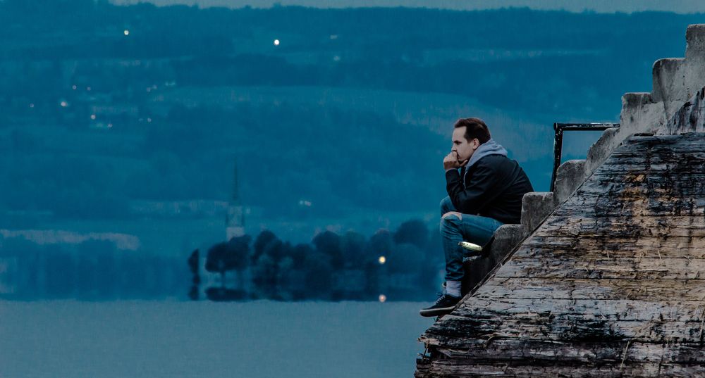 Man sitting at the dock in twilight, thinking about the meaning of life