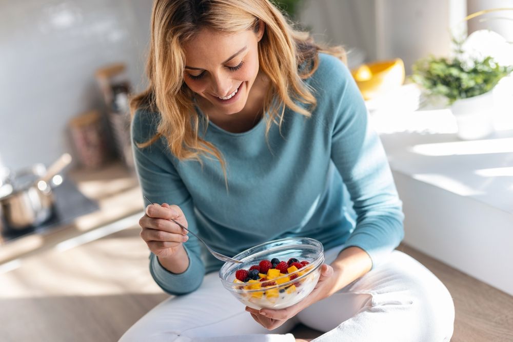 Shot of kind beautiful woman eating a healthy fruit bowl