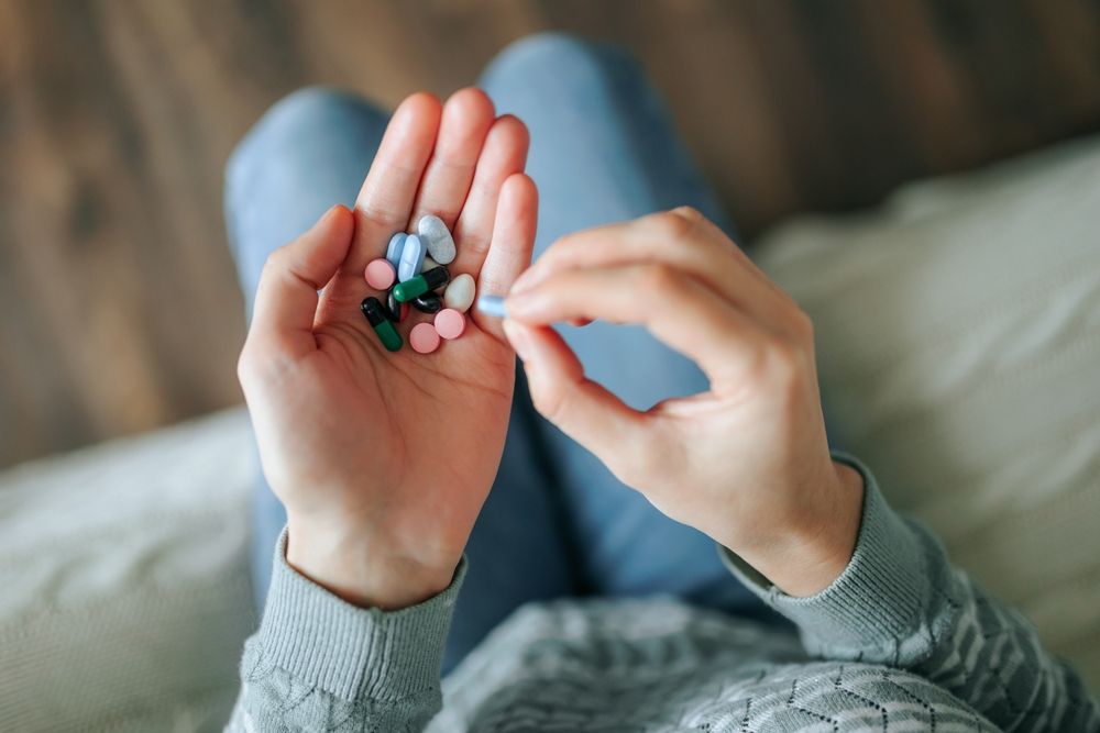 a white woman holding a single capsule pill between the thumb and index finger
