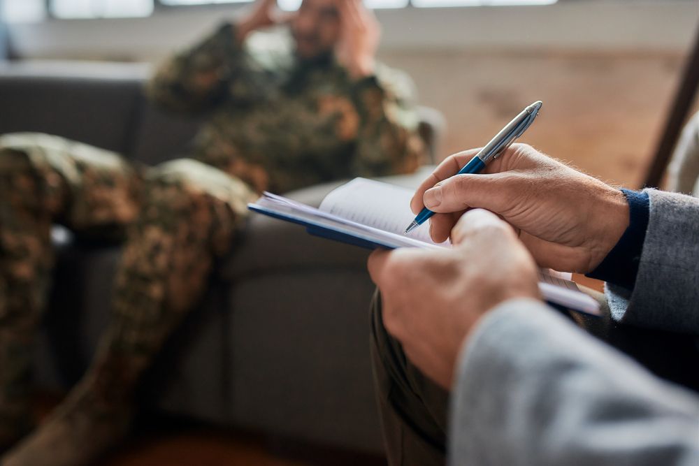A close-up of a psychologist's hands making notes while communicating with someone during therapy