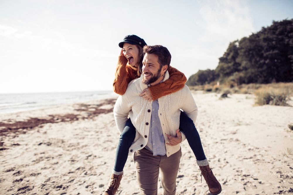 Young smiling couple enjoying piggyback ride and laughing