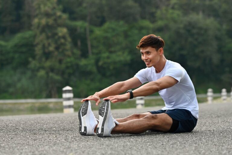 An Asian Male athlete in sportswear stretching legs before jogging, showing flexibility and proper warm-up technique.