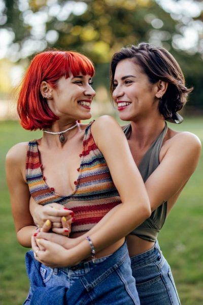 Girls in a park, lgbt couple in a hug, looking and smiling at each other.