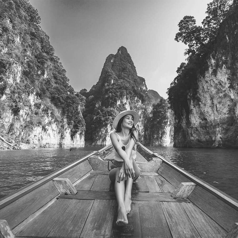 Happy solo traveler asian woman with hat relax and sightseeing on Thai longtail boat