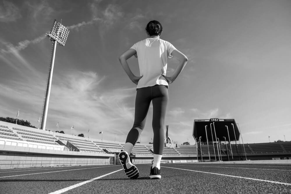 Woman warming up by stretching before starting a run at the track and field stadium