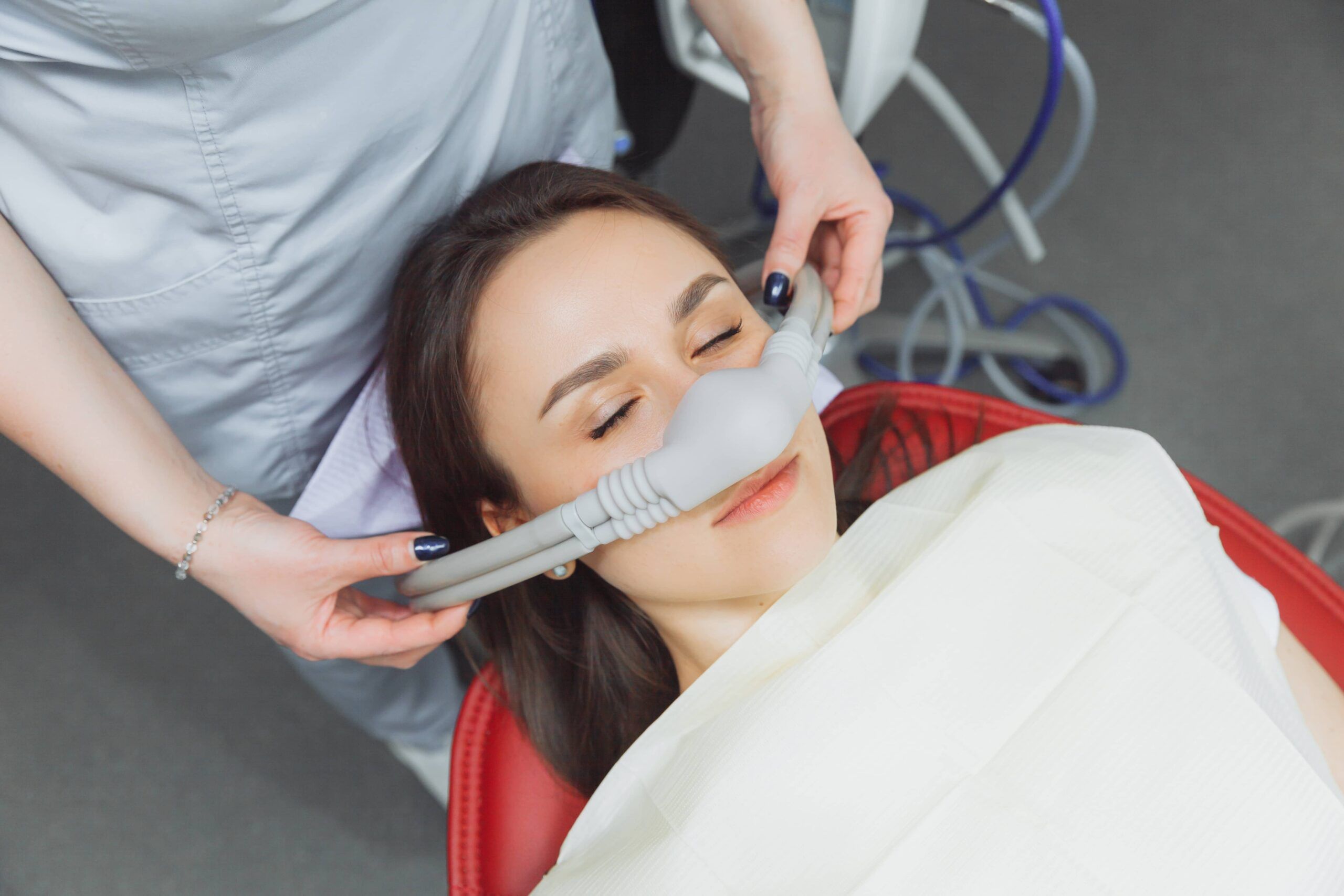Nitrous Oxide, dentist puts inhalation sedative mask on his patient.