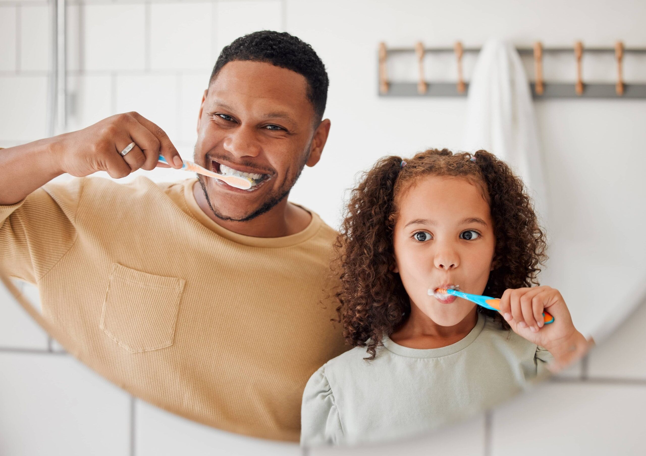 father and child brushing teeth in a family home bathroom for dental health