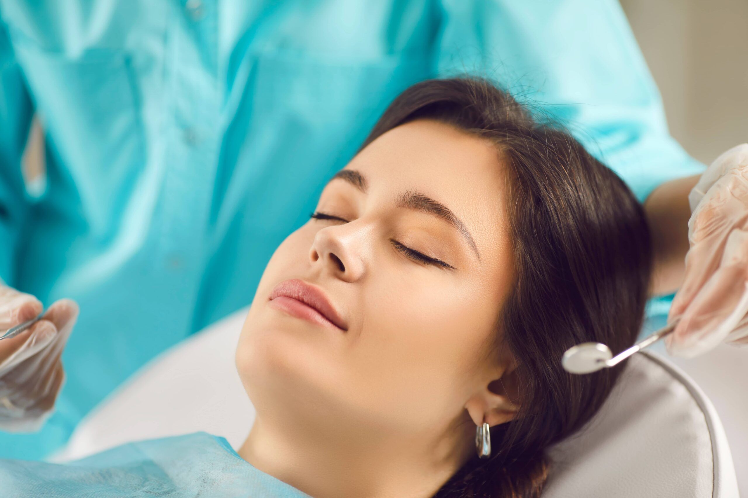 Beautiful young woman closed her eyes in the dentists chair, close-up of her face.