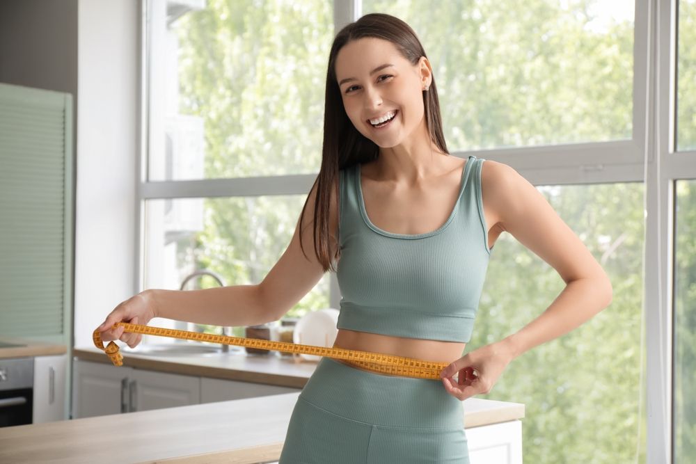 Beautiful young happy woman with measuring tape