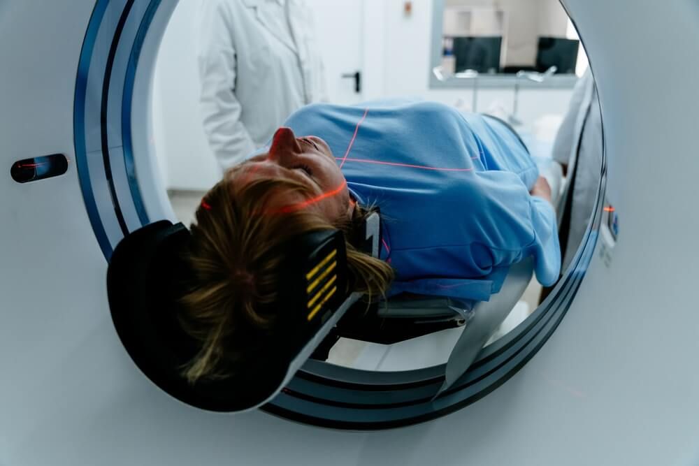 Mature female patient lying on table entering MRI machine in hospital setting