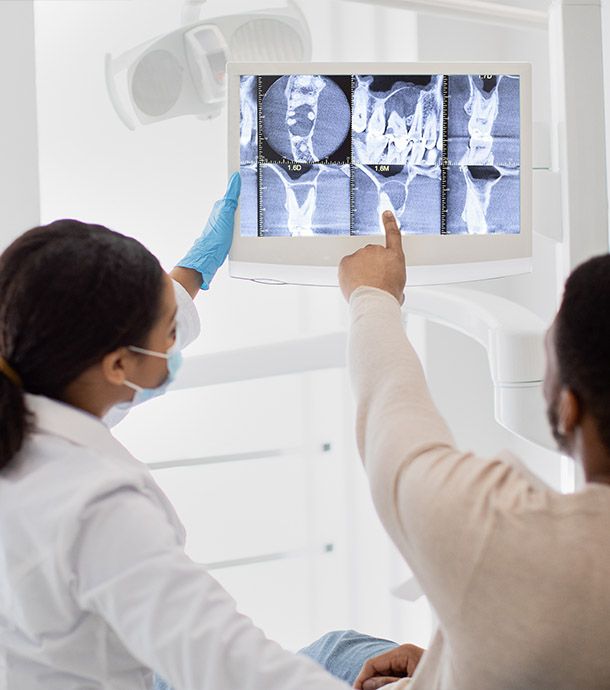 female dentist pointing at teeth X-ray image on screen during consultation on dental surgery in clinic