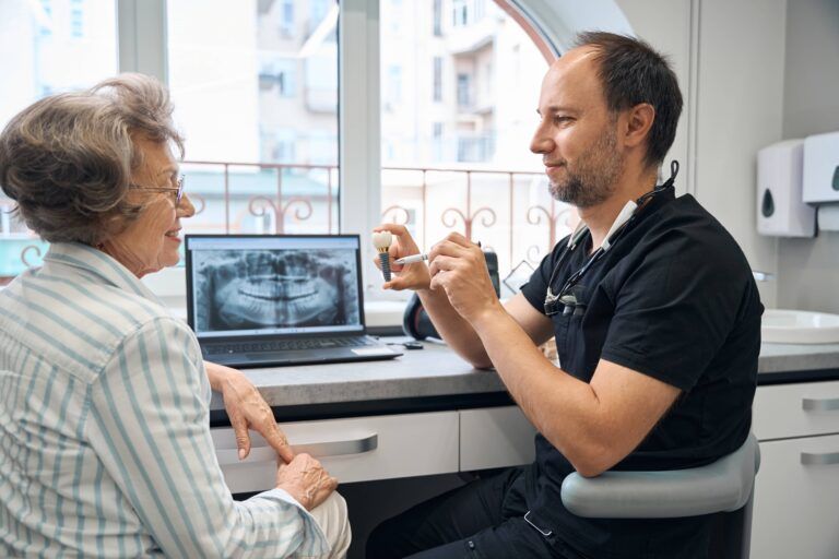 Middle-aged man shows a model of dental implant to patient