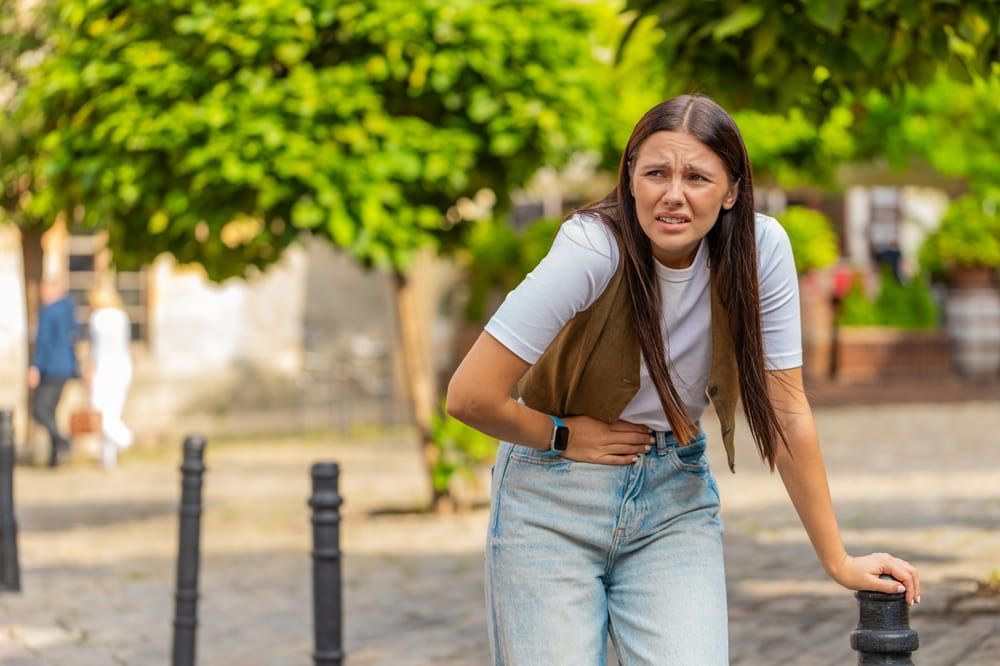 Upset tourist lady having symptom poisoning diarrhea indigestion peptic ulcer pancreatitis on city street