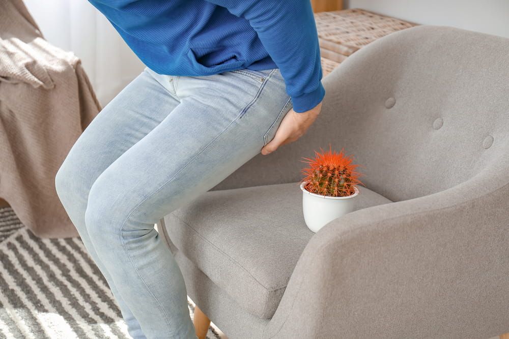 Young man near armchair with cactus at home