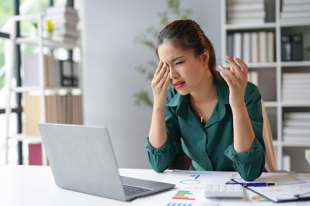 Young professional woman feeling eye strain after long hours working on computer,