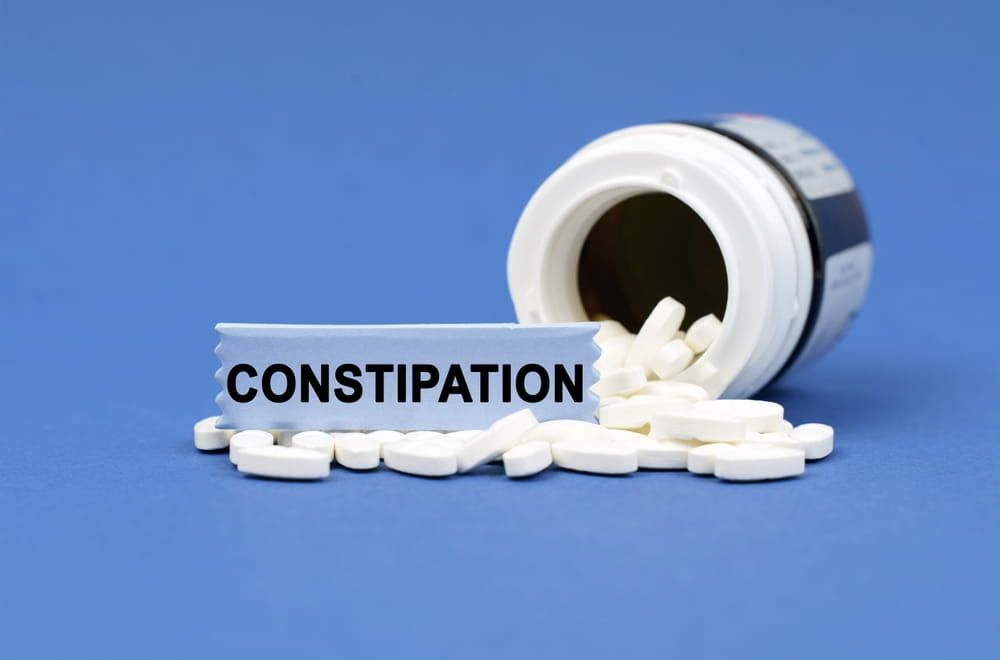 Medical concept. On a blue surface lies a jar of pills and a sign with the inscription - CONSTIPATION