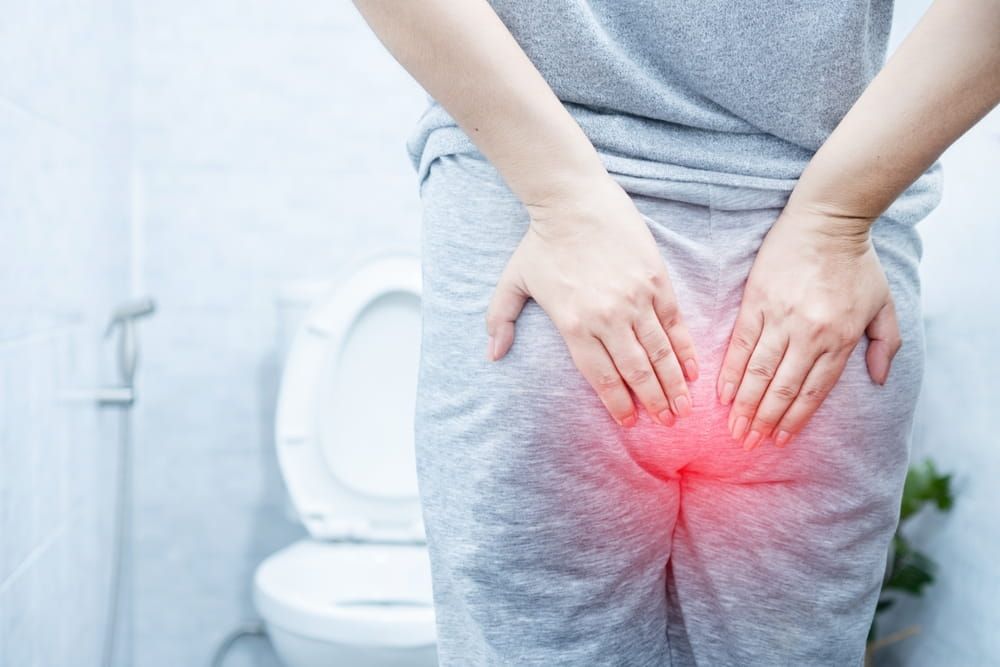 woman suffering from hemorrhoids hurting and bleeding during bowel movements in a toilet